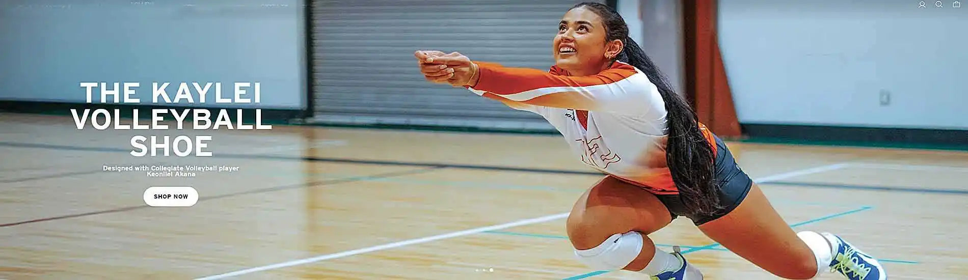 A female volleyball player in action on a court, wearing an orange, white, and black uniform with white socks and blue and yellow athletic shoes.