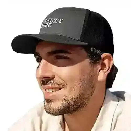 Black trucker-style cap with a mesh back and embroidered white text on the front panel.